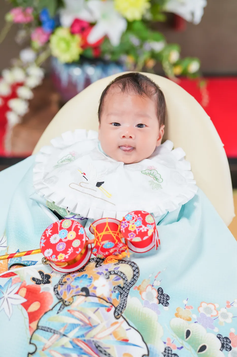 水色の祝い着をかけて、でんでん太鼓と撮影したお宮参りの赤ちゃん
