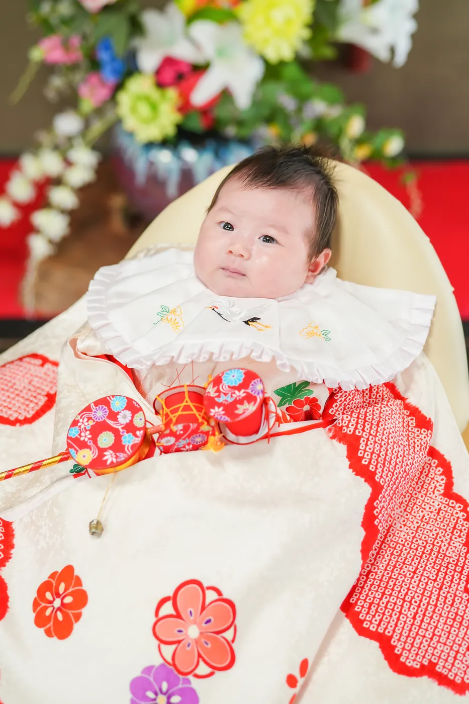 白地に赤の祝い着をかけたお宮参りの赤ちゃん