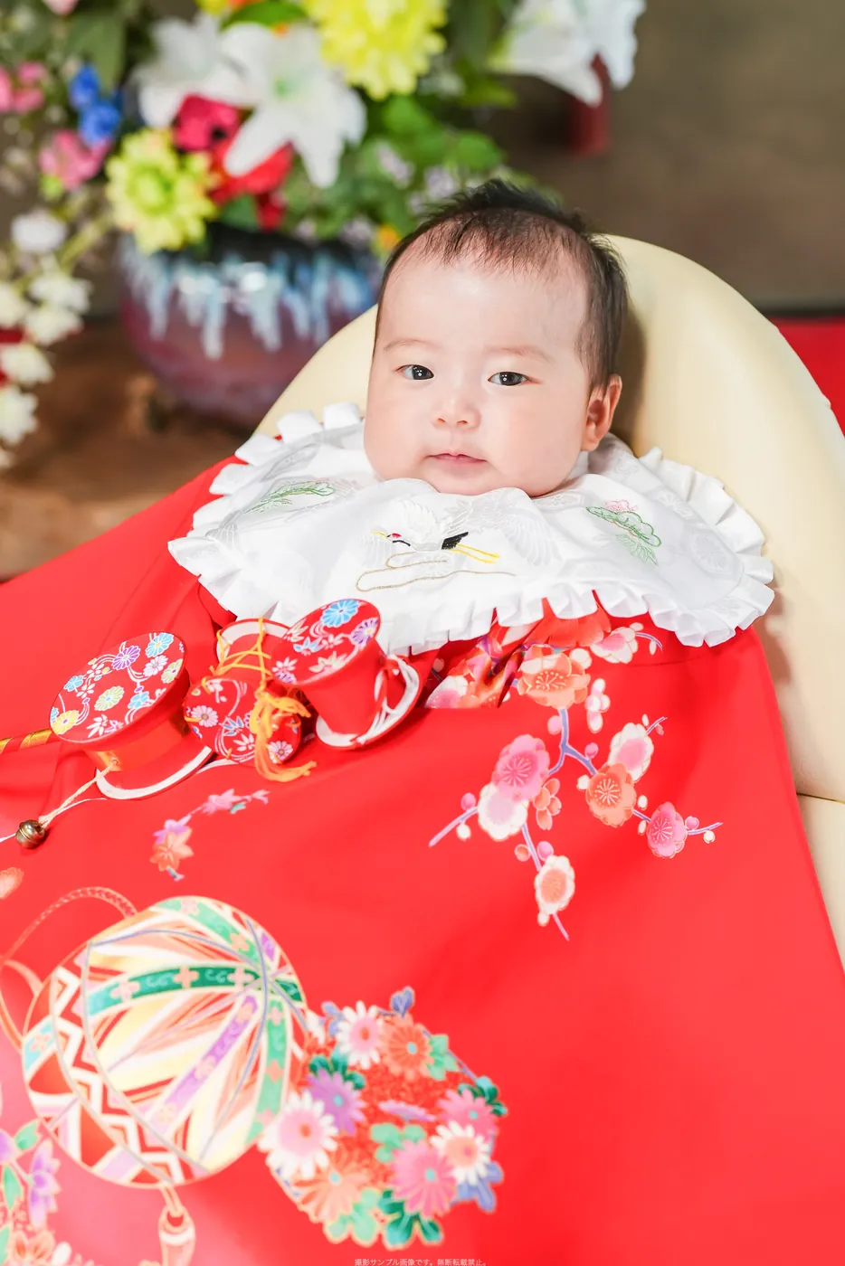 赤い祝い着とでんでん太鼓で撮影したお宮参りの赤ちゃん