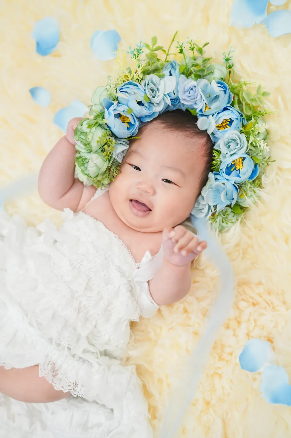 お花の冠で手をあげて笑う赤ちゃん