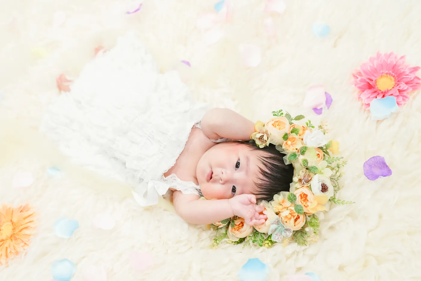 お花の冠をつけて、ふわふわの上でねんねする赤ちゃん