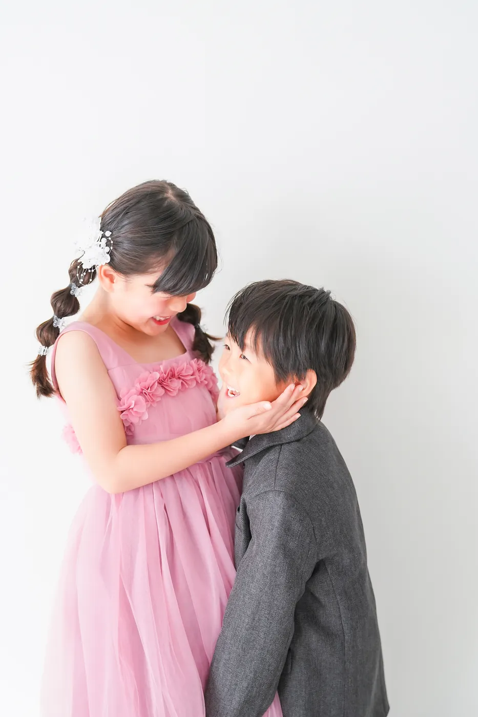 ピンクのドレスの姉とスーツを着た弟のきょうだい写真
