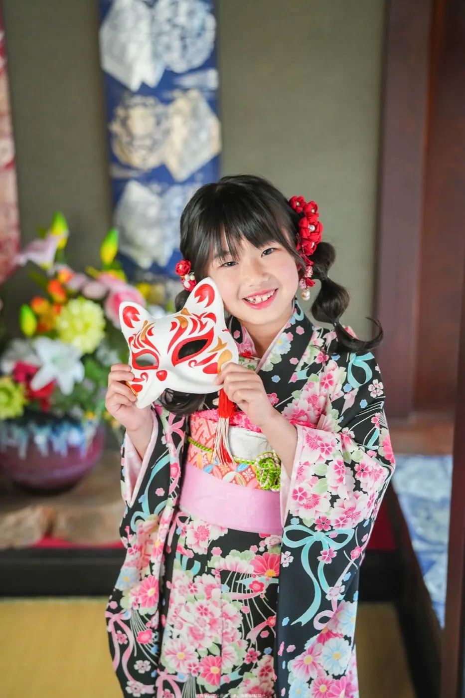 狐のお面を持つ7歳女の子の着物姿