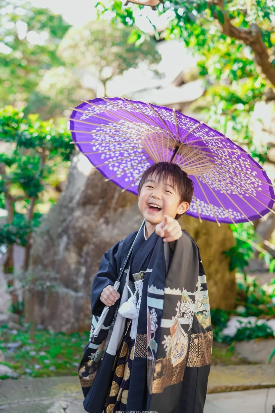 紫の和傘を持って笑う羽織袴の男の子